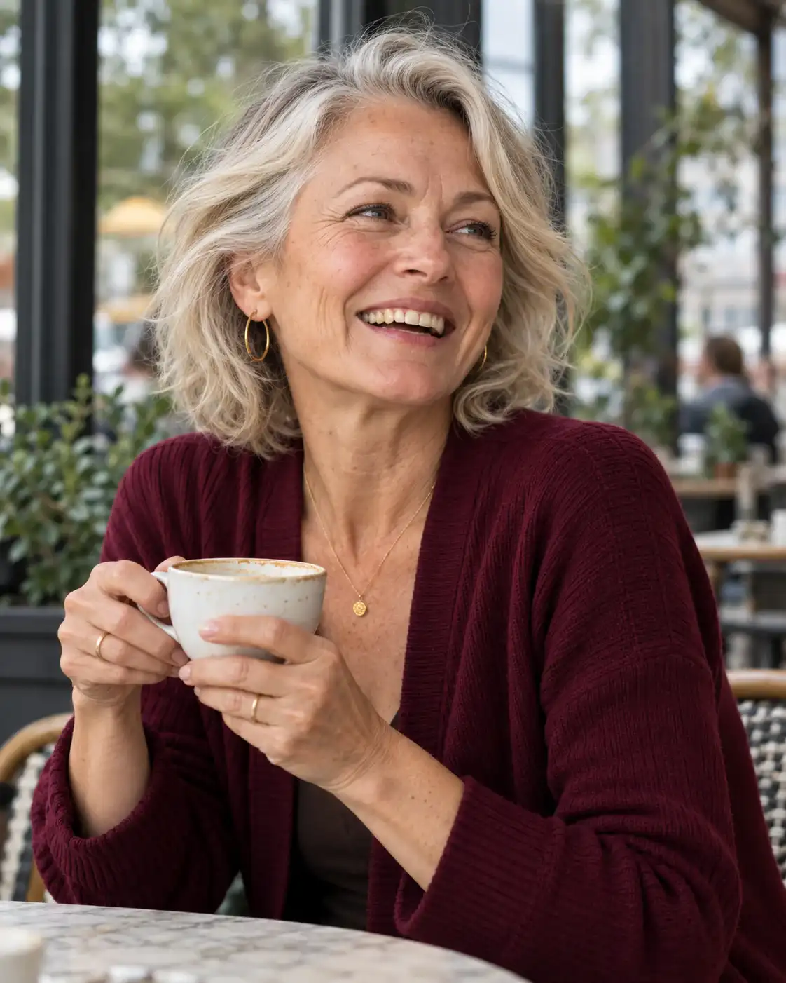 Smiling silver-haired woman enjoying coffee outdoors